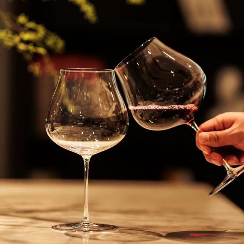 Two Persephaure wine glasses meeting in a toast at an intimate table